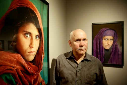 US photographer Steve McCurry poses next to his photos of the "Afghan Girl" named Sharbat Gula at a 2013 exhibition in Hamburg, northern Germany. - DPA/AFP/Lehaz Ali