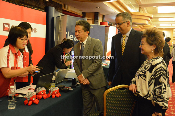 Tan being briefed by a CIMB officer as B Ravintharan (second right) and Chuah (right) look on. 