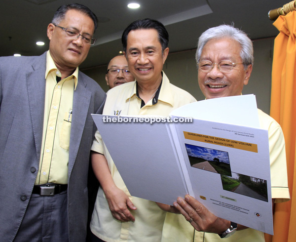 Masing (right), accompanied by Zuraimi and Safri (left), looks at a book presented to him by JKR.