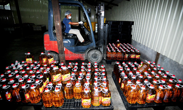 A worker arranging cooking oil bottles at a warehouse. – Bernama file photo