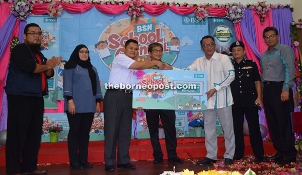 Zamri (third right) hands over a mock cheque to Saidal, witnessed by Dr Annuar (fourth left) and (from left) Kassim, Salemah and others.