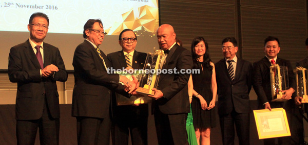 Abang Johari (second left) presents the Sarawak State Outstanding Entrepreneurship of the Year 2016 award to Naim Holdings Berhad managing director Datuk Hasmi Hasnan. From left are Assistant Minister for Industrial Development (Investment and Promotions) Datuk Julaihi Narawi and SCCI president Datuk Abang Abdul Karim Tun Openg. — Photo by Jeffery Mostapha