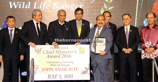 Adenan (third left) presents the Outstanding Honorary Wild Life Ranger award to John. From left are Naroden, Awang Tengah, Wong, Len, state legal counsel Datuk JC Fong and Mulu assemblyman Datuk Gerawat Gala. – Photo by Chimon Upon