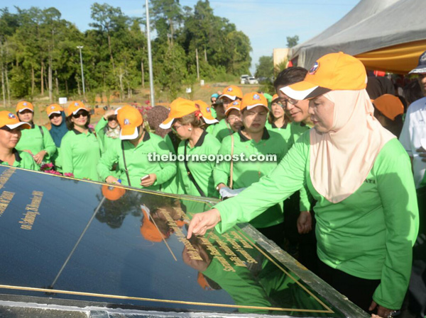 Jamilah (right) signs on a plaque at the entrance to Taman Tranquilty Sabati.