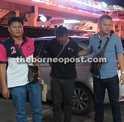 The suspect (centre) being escorted by CID personnel to Miri Central police station. 