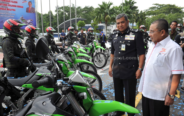 Khalid (second right) Felda chairman Tan Sri Mohd Isa Samad (right) looking at the Kawasaki KLX250 motorbikes after witnessing the handing over of the motorcycles to the Royal Malaysia Police in Kuala Lumpur. — Bernama photo 