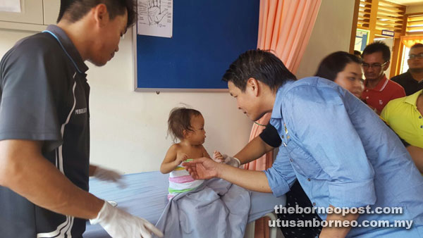 Dennis (right) comforts the Penan child being treated at Long Jekitan Rural Clinic in Baram.