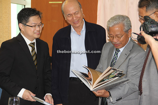 Masing looking at a book presented by Miros. From left are Dr Wong and Lee. 