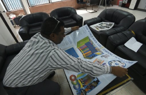 Indian salesman John Gunti carries fold-out promotional material to help with his sales pitch. -AFP/ Ian Timberlake