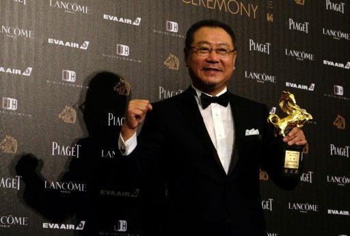 Chinese director Feng Xiaogang displays a trophy after winning the Best Director during the 53rd Golden Horse Film Awards in Taipei on November 26, 2016. - AFP