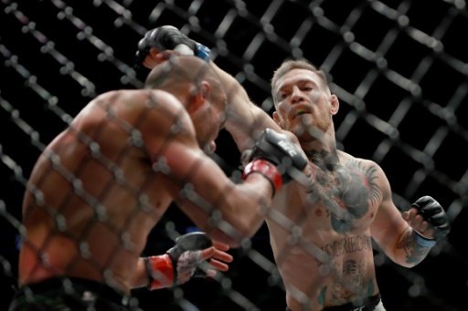 Ireland's hugely popular UFC featherweight champion Conor McGregor (R) knocked Eddie Alvarez down three times in the first round before finishing him off in the second. AFP Photo