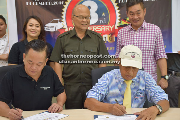  Tan (seated, left) and Samat sign the MoU documents, witnessed by Minos (standing, centre). Grace is at Minos’ right.