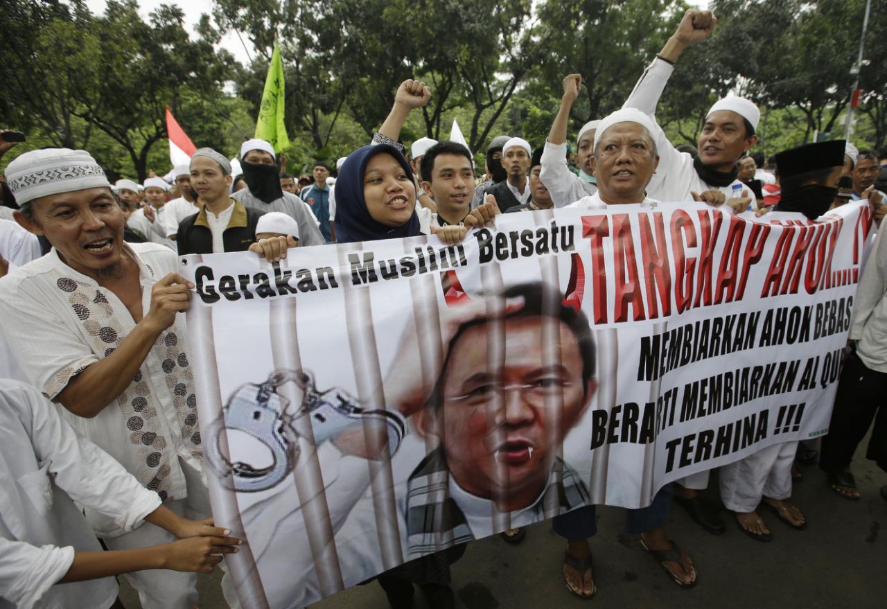 In this Friday, Oct. 14, 2016, photo, Muslim protesters hold a banner calling for the arrest of Jakarta's ethnic Chinese and Christian Governor Basuki Tjahaja Purnama, popularly known as "Ahok", outside the City Hall. Indonesian police are planning a massive show of force in the capital Jakarta on Friday to contain a much-hyped protest by Muslim hardliners against the city's popular governor that threatens to ignite the country's religious and racial flashpoints. AP Photo