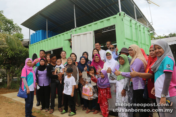 Fatimah (front, fifth right) and Ting (standing left at door) and others pose in front of the container home. Also seen is Sarawak Islamic Education Service Bureau director Datu Dr Adi Badiozaman Tuah (standing right at door). 