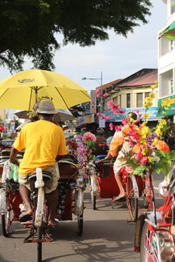 Trishaws ferrying tourists along a busy street in Penang.