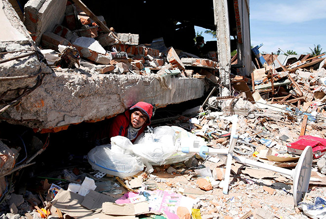 A man retrieves fans from a collapsed shop following a strong earthquake in Meureudu, Pidie Jaya, Aceh province. — Reuters photo