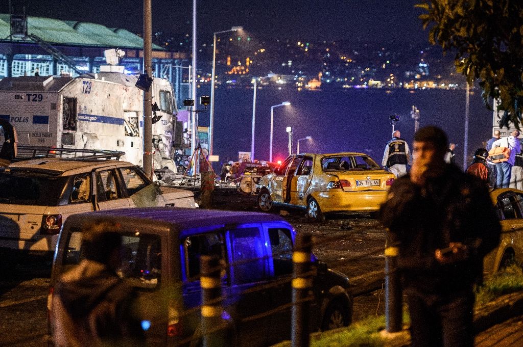 Turkish police officers and forensic work next to damaged police vehicles and cars on the site where a car bomb exploded near the stadium of football club Besiktas in central Istanbul on Dec 10, 2016. AFP Photo