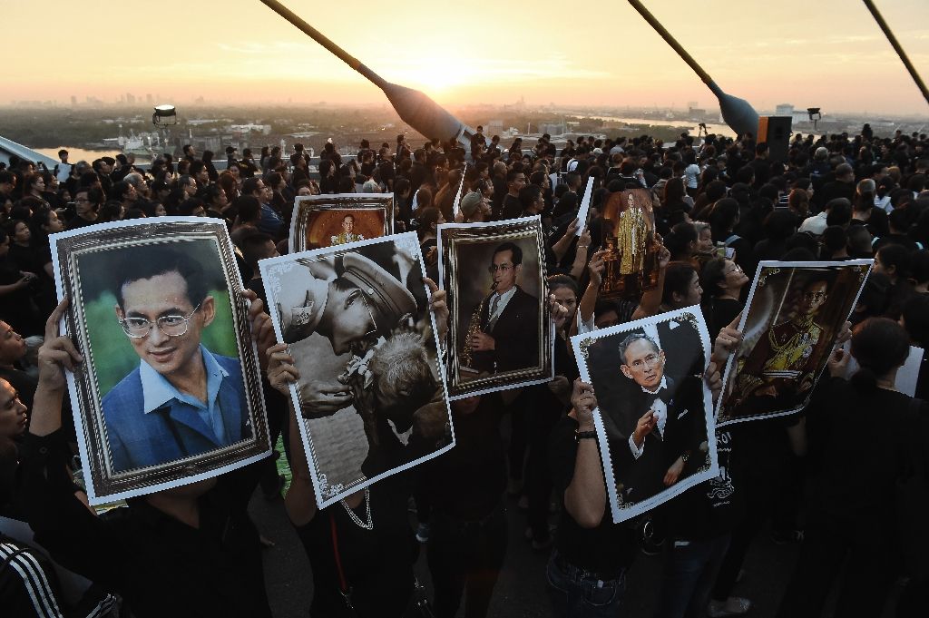 Mourners hold pictures of the late Thai King Bhumibol Adulyadej as people gather to commemorate his birthday, on Bhumibol Bridge in Bangkok, on Dec 5, 2016. AFP Photo