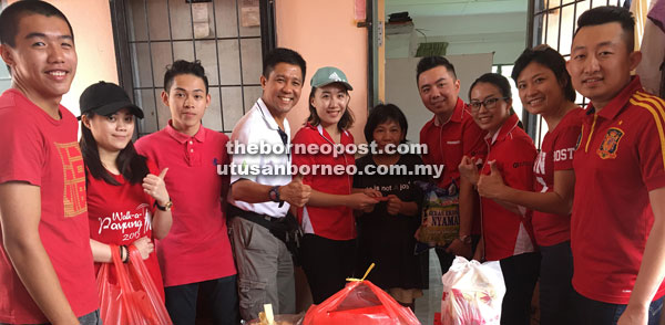 Volunteers handing over donations including red packet to a recipient. Kelvin is at fourth left.