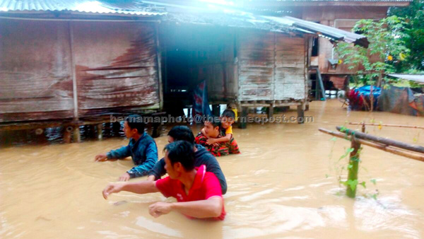 PARAS BAHAYA: Anggota Jabatan Bomba dan Penyelamat membantu memindahkan penduduk di Kampung Merion semalam. — Gambar Bernama 