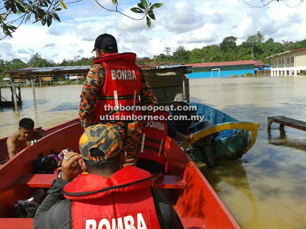 PANTAU: Anggota bomba membuat pemantauan keadaan banjir di SK Nanga Penyarai Tatau, semalam.