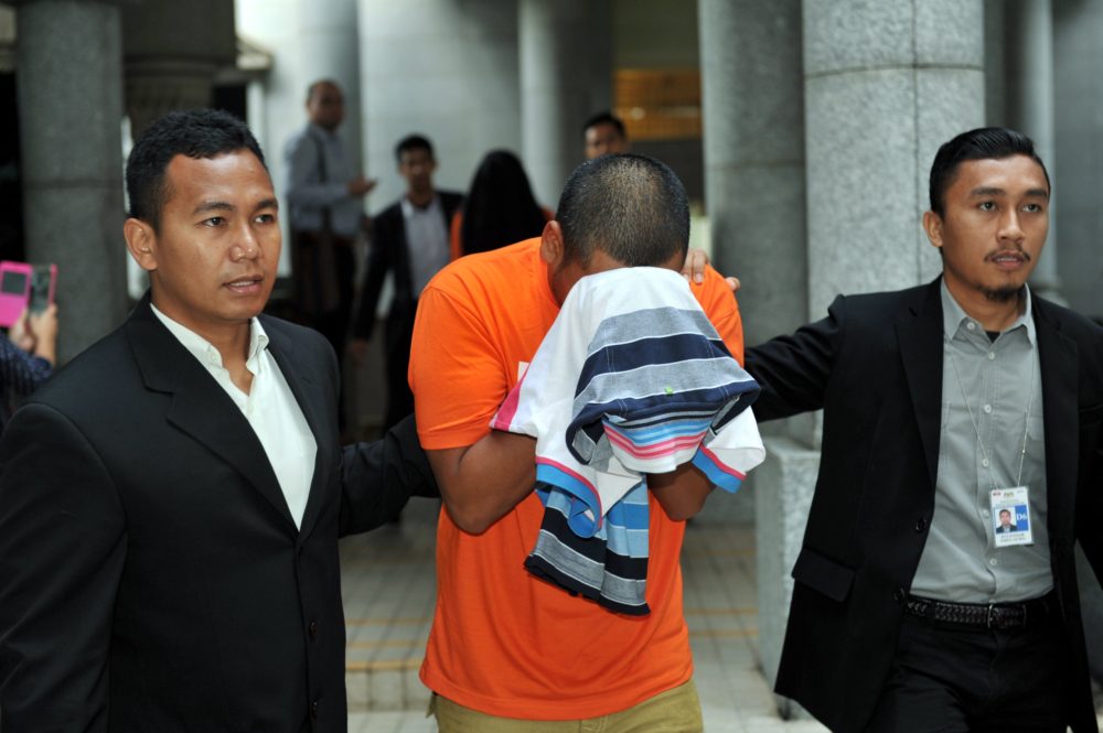 One of the sons is led out of court by MACC officers. Bernama Photo