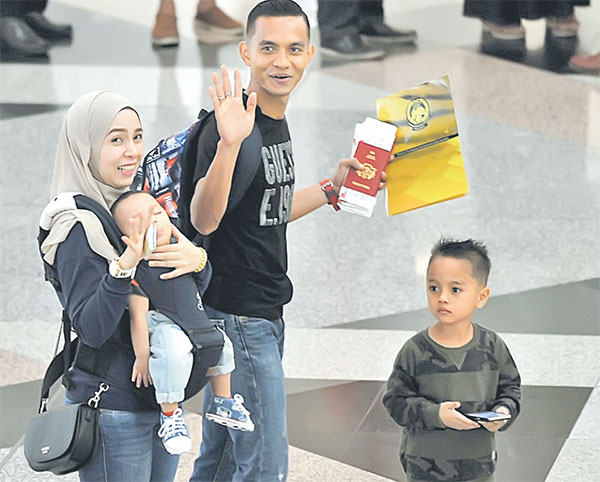 BANGGA: Faiz Subri (tengah) bersama isteri Nur Zawanis Hashim, 29 dan dua anaknya, Akief Fayyadh, 4, dan Muhammad Aqil Zayyan, 7 bulan memasuki kawasan perlepasan Antarabangsa KLIA semalam. — Gambar Bernama