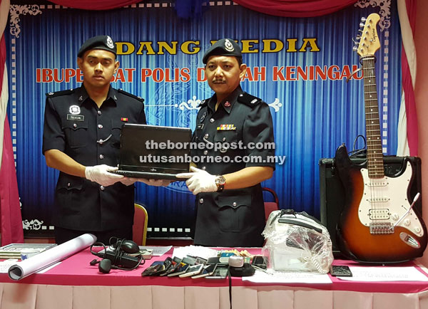 Ahmad (right) and his officer showing the stolen laptop and other items seized from the two suspects in the night burglary cases.