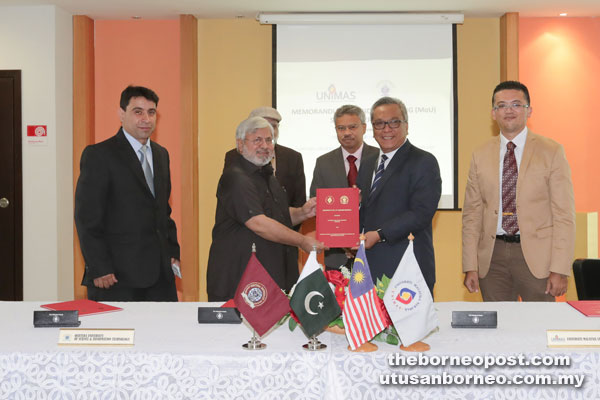 Mohamad Kadim (second right) of Unimas exchanging the signed MoU documents with Muhammad Azhar of Qurtuba University.