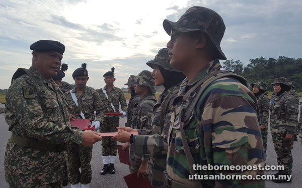 Mundaw (left) presenting a certificate to one of the participants at Muara Tuang Camp yesterday.