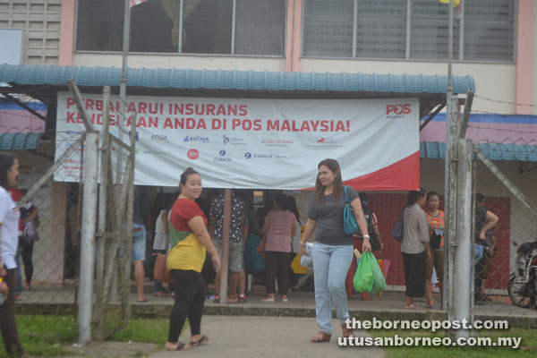 Photo shows some members of the public queuing outside the post office.