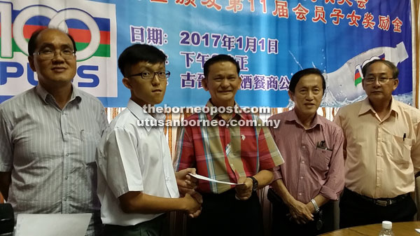 Teo (centre) presents an incentive to an association member’s child during the AGM. 