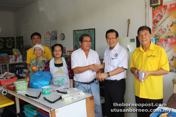Lee (second right) distributes mandarin oranges to the traders at the city’s business centre area while Ting and SUPP Senadin branch’s publicity chief Erick Chin look on.