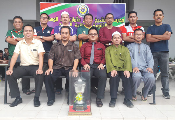 Organising chairman Zulkaranainhisham Sarbini (left, standing) and SMK Agama Anuar Kiprawi, senior assistant for co-curriculum (seated second left), posing with representatives of participating schools after the draw and meeting at SMKA Shoaw yesterday.