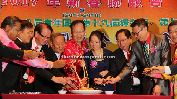 Henry (fifth left) joins (from left) Kong, Hii, Albert, Kiu Kiong, Jiang Ying, Vincent and other guests in the traditional tossing of the ‘yee sang’ at the event in Sibu.