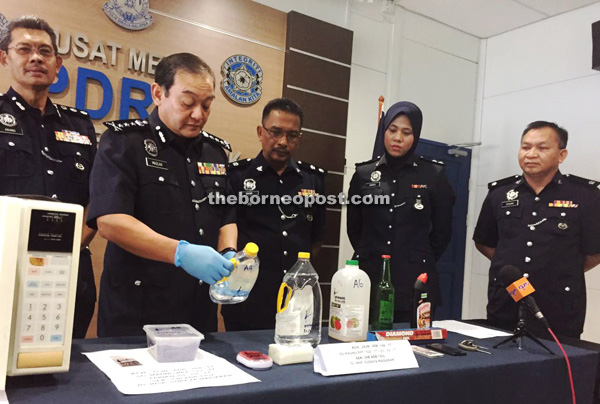 Mazlan takes a closer look at a bottle containing one of the chemicals used to manufacture the Syabu. From left are Abang Ahmad, Sahar, investigating officer Inspector Suraya Maisarah, and Sekam. 