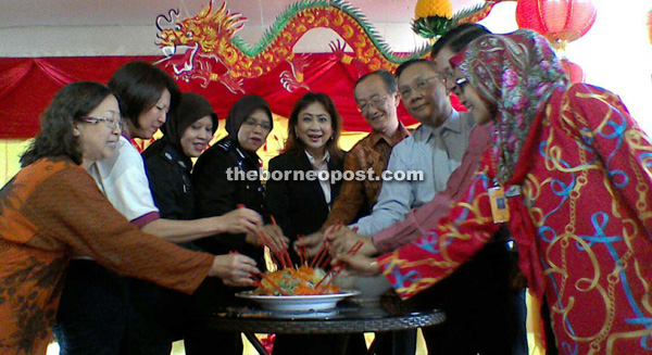 Nora (fourth from left), Katherine (middle), Charles (fourth from right) and Wil-liam (third from right) tossing the yee sang to celebrate the Chinese New Year during the Jalinan Kasih programme at Kota Kinabalu Women's Prison.