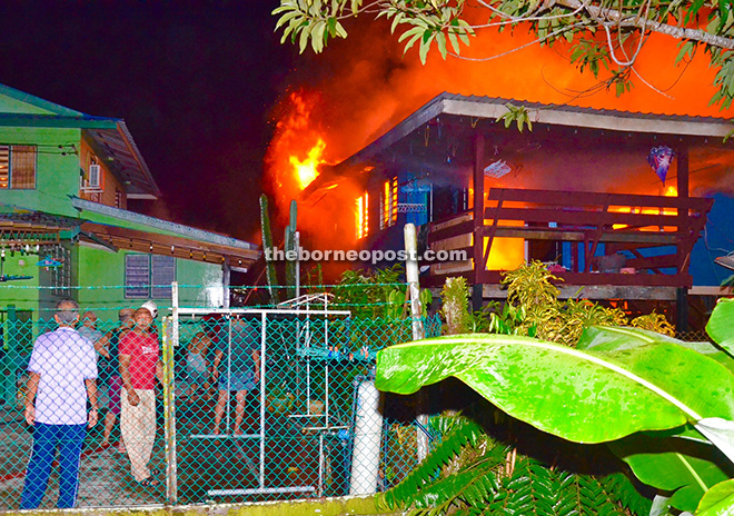 HELPLESS: Residents of Kampung Bahagia Jaya in Sibu can only look at a house of their fellow villagers being engulfed in flames. Fire struck five houses at the village early yesterday, razing two of them to the ground and causing serious damage on the remaining three. No casualty was reported. — Photo by Anna Siaw