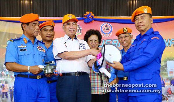 Wan Junaidi (third left) presents a hailer to a member of the force at the function, as Feona, Azmy (left) and others look on. — Photo by Muhammad Rais Sanusi