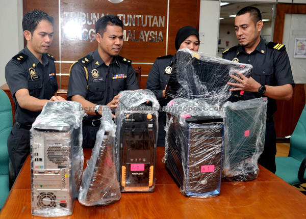 Abdul Wahid (second left) showing the computers that were seized during a press conference. — Bernama photo