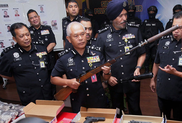 Mohmad Salleh (second left) shows a confiscated rifle at the press conference. — Bernama photo