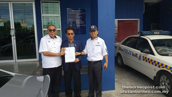 Cheng (centre), together with Buang (left) and Igat hold the police report.