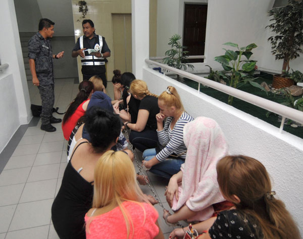 Immigration officer checking foreign women in the apartment after the operation. — Bernama photo 