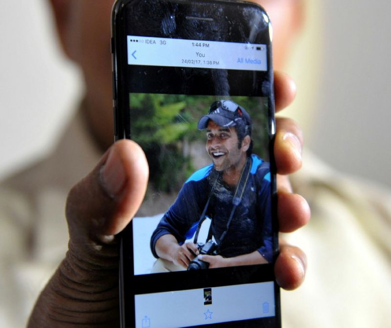 Indian man Jagan Mohan Reddy holds a smartphone with an image of his son Alok Madasani at his residence in Hyderabad on Feb 24, 2017, after Alok was injured in the shooting of two Indian men in the US state of Kansas. aFP Photo