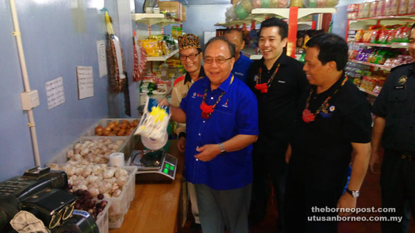 Henry weighing a bag of flour to see if the scale was in order, during a visit to a KPDNKK POS in Bario as others look on.