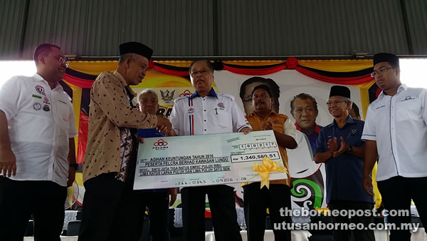 Ismail (centre) presents a mock cheque bearing the total dividends for 2016 to Japar. Also seen are Bung Moktar (third left, partly obscured) and Azizul (right).