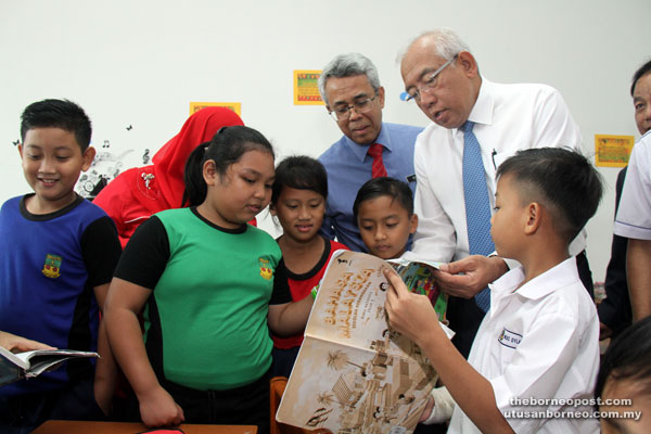 Mahdzir (right) goes through a book with pupils during a visit to SK St Martin Merdang.