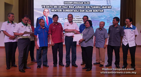 Wan Junaidi (fifth left) distributes the fund to the JKKKs while others look on.