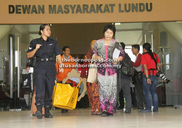 A presiding officer and her team accompanied by a policewoman bring the EC yellow polling bag and other related materials from Lundu Community Hall to Lundu police station. — Photos by Chimon Upon