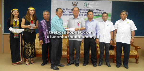 Penghulu Herbert Lawai (fourth left) representing the recipients from Long Terawan receive the cheques from Gerawat while others look on.